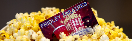An image of a red Fridley Theatres gift card sticking out of a mound of buttery yellow popcorn